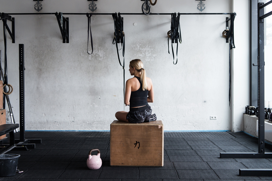 Blonde sportliche Frau in der Crossfitbox sitzt auf einem Kasten