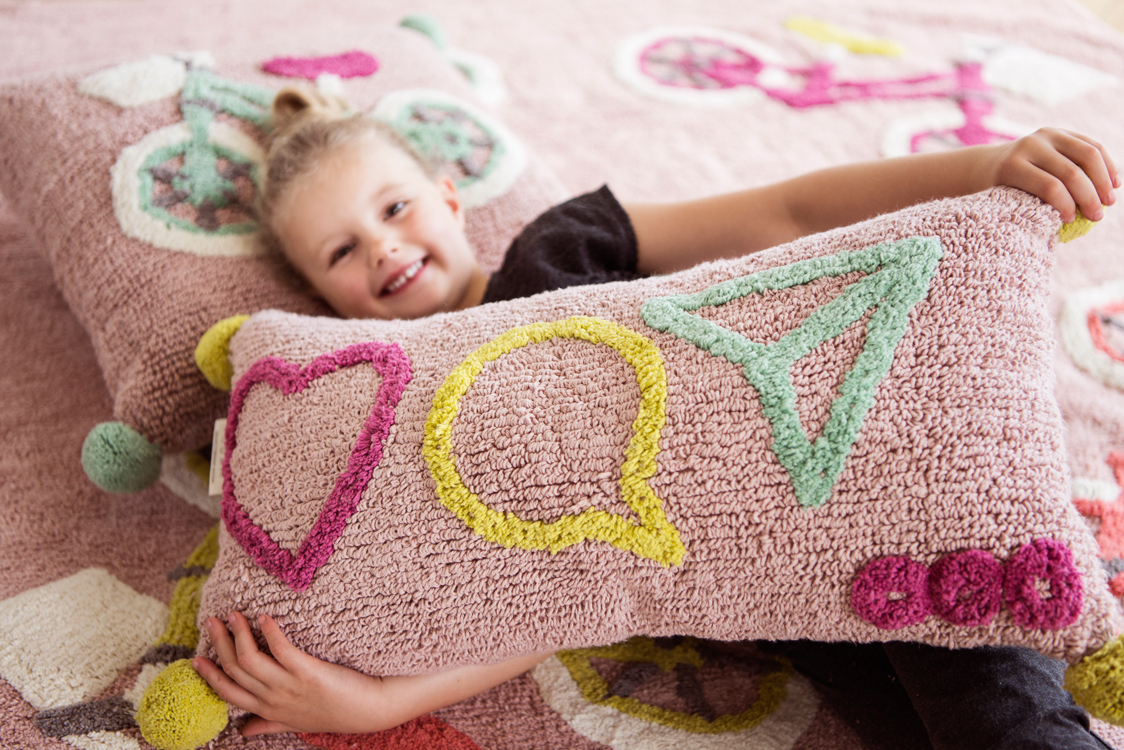 Blondes Mädchen lächelt in die Kamera und liegt auf einem Teppich in einer Altbauwohnung
