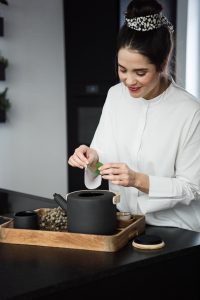 Frau zupft Kräuter für Tee im Japandi Look
