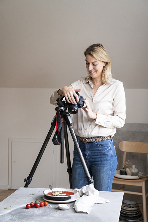 People Portraitfotografie und Lifestyle Fotografie in Kiel und Hamburg Blonde Frau in Cremetönen hält Stapel an Schüsseln in der Hand und blickt in die Kamera