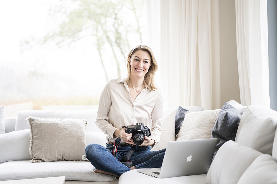 People Portraitfotografie und Lifestyle Fotografie in Kiel und Hamburg Blonde Frau in Cremetönen hält Stapel an Schüsseln in der Hand und blickt in die Kamera