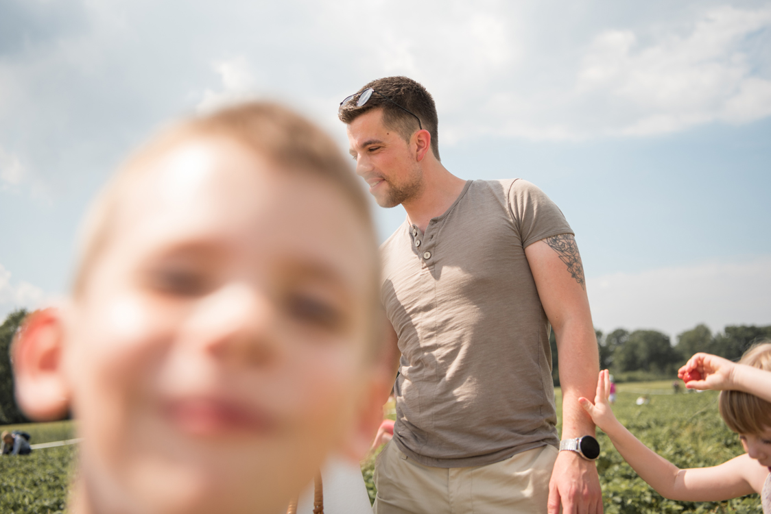 Kidsfotografie Lifestylefotografie in Hamburg für Social Media Familie pflückt Erdbeeren im Erdbeerfeld