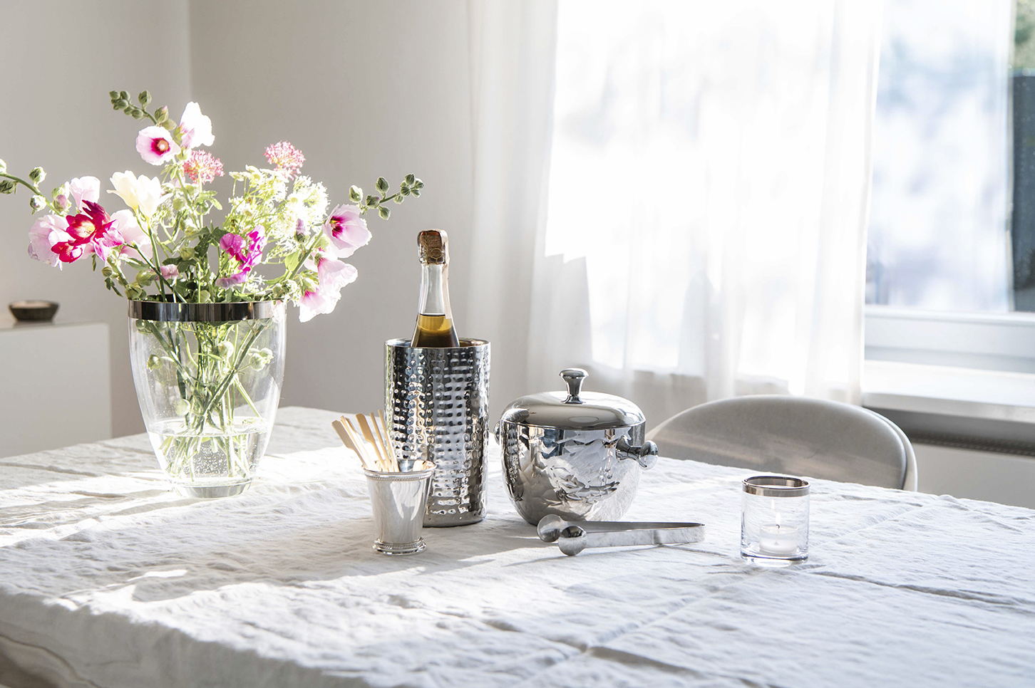 Interiorfotografie Stilllife in Hamburg, Sektkühler und Eiswürfelbehälter auf einem Tisch mit Leinendecke