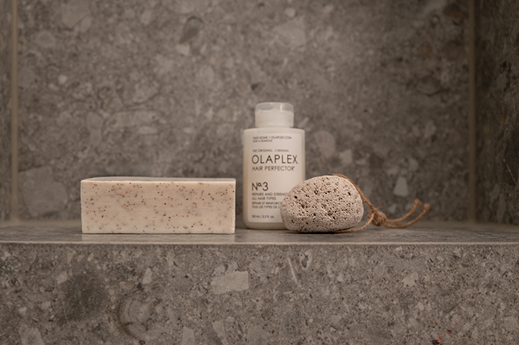 Detailaufnahme von Pflegeprodukten auf Ablage aus grauem Naturstein in modernem Badezimmer in der HafenCity Hamburg