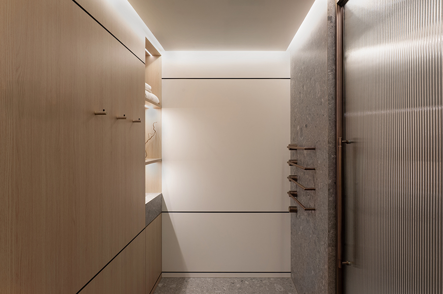 Moderner Flur mit Holzfronten, integrierter Beleuchtung und Natursteinwand in der HafenCity Hamburg