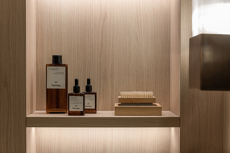 Detailaufnahme von Pflegeprodukten in beleuchtetem Holzregal im modernen Badezimmer in der HafenCity Hamburg