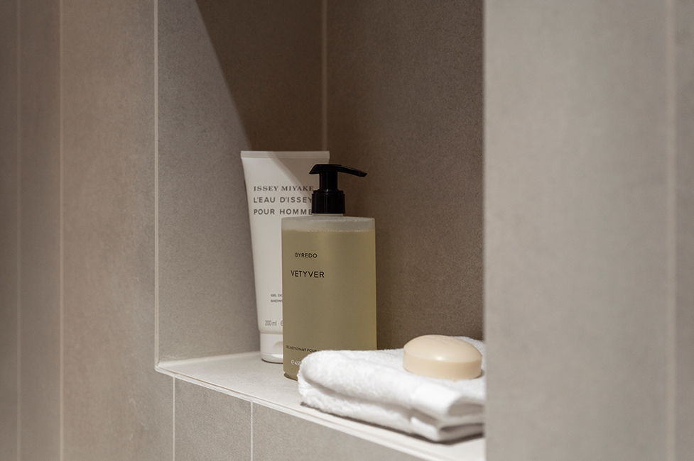 Detailaufnahme eines Badezimmerregals mit Handtuch, Seife und Pflegeprodukten in einer Nische aus Naturstein in der HafenCity Hamburg