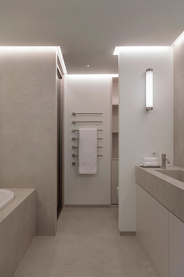 Modernes Badezimmer mit heller Natursteinverkleidung, indirekter Beleuchtung und klarer Linienführung in der Hamburger HafenCity