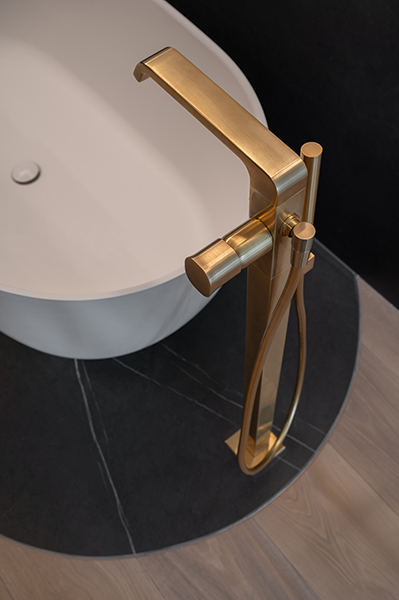 Freistehende Badewanne mit goldener Armatur auf dunklem Natursteinboden, Interiorfotografie eines modernen Badezimmers in der Hamburger HafenCity.