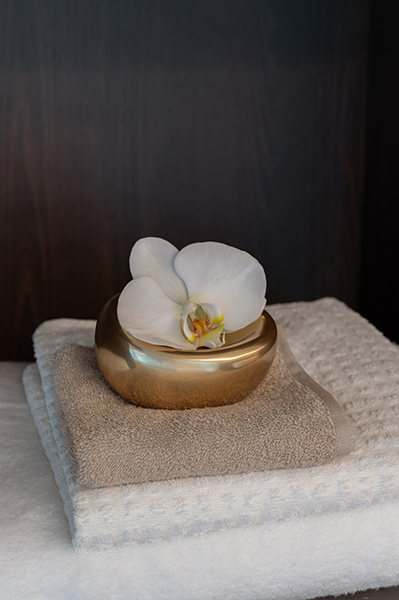 Detailaufnahme einer gefalteten Handtuchablage mit goldener Dose und weißer Orchidee, Interiorfotografie in der Hamburger HafenCity.