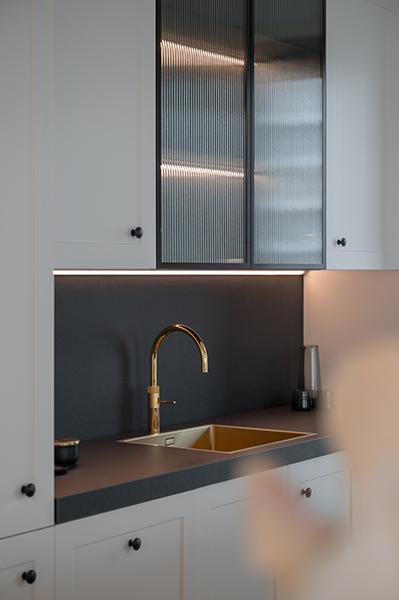 Modernes Badezimmer-Detail mit goldener Armatur, grauer Marmoroberfläche und indirekter Beleuchtung in der HafenCity Hamburg