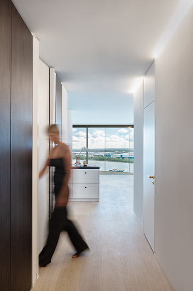 Weitwinkelaufnahme eines modernen Flurs mit Blick ins Badezimmer und auf den Hafen in der HafenCity Hamburg, mit gehender Person in Bewegung