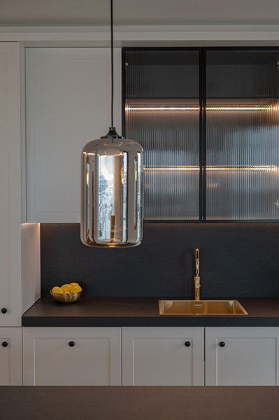 Moderne Küchenzeile mit goldener Armatur, dunkler Arbeitsplatte und Glasfronten in der HafenCity Hamburg