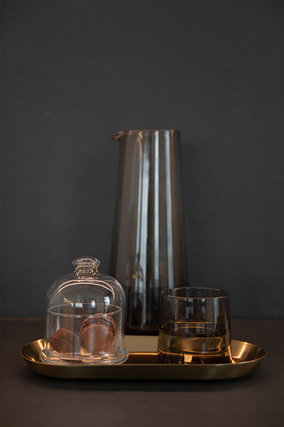 Stillleben mit Glaskaraffe, Trinkglas und goldener Ablage auf dunkler Oberfläche in einem modernen Badezimmer in der HafenCity Hamburg