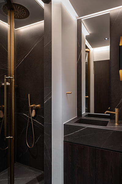 Modernes Badezimmer mit dunklem Marmor, goldenen Armaturen und indirekter Beleuchtung in der Hamburger HafenCity