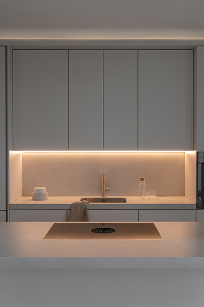 Minimalistische Küchenfront mit heller Arbeitsfläche und sanfter Beleuchtung, Interiorfotografie in Hamburg-Sandtorhafen Hafencity