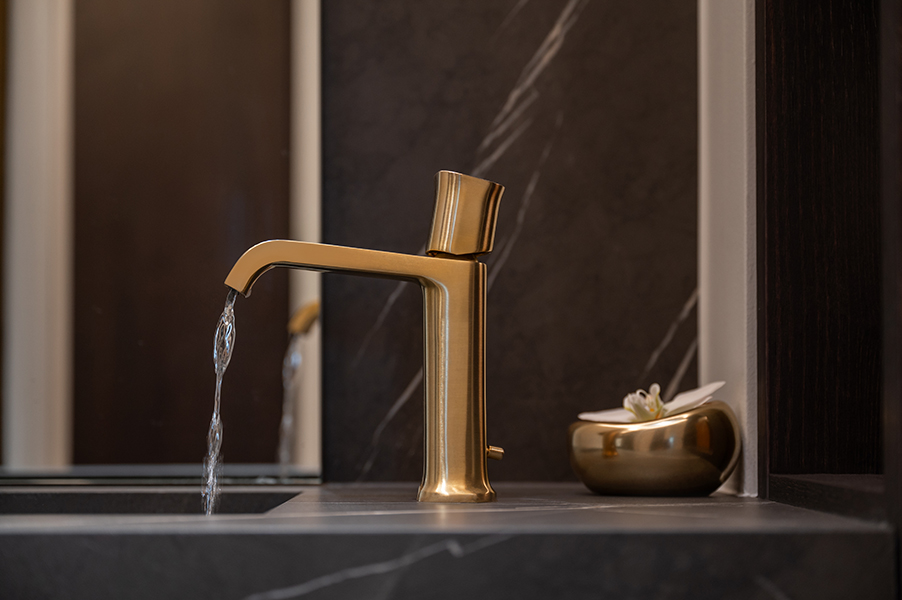 Goldene Armatur über dunkler Marmoroberfläche in modernem Badezimmer in der HafenCity Hamburg