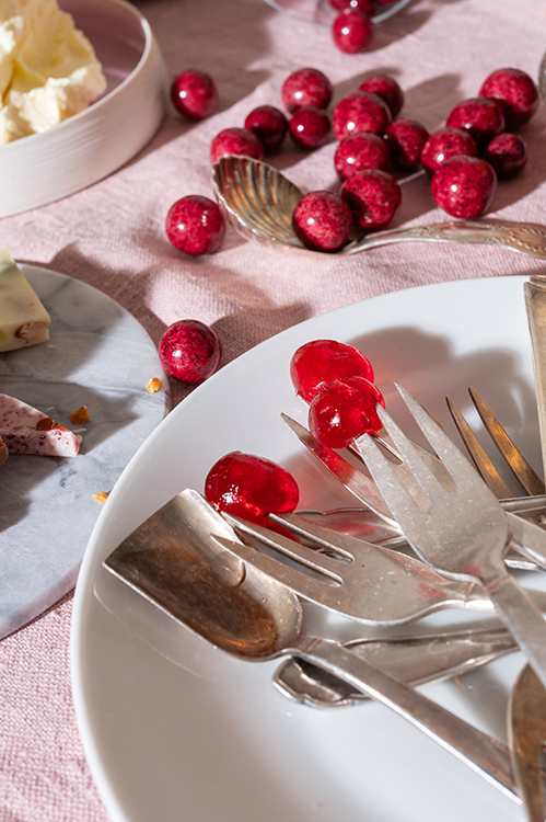Besteck mit roten Süßigkeiten auf Teller, detailreiche Food Lifestyle Fotografie