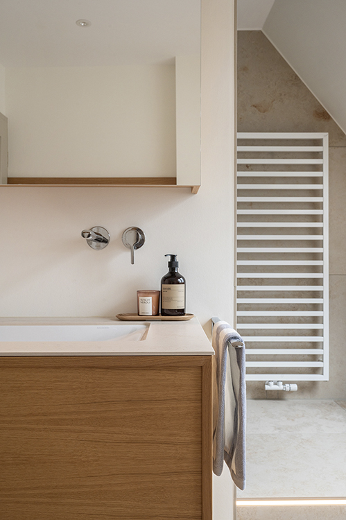 Calm bathroom interior with custom wooden vanity, natural stone surfaces and soft daylight