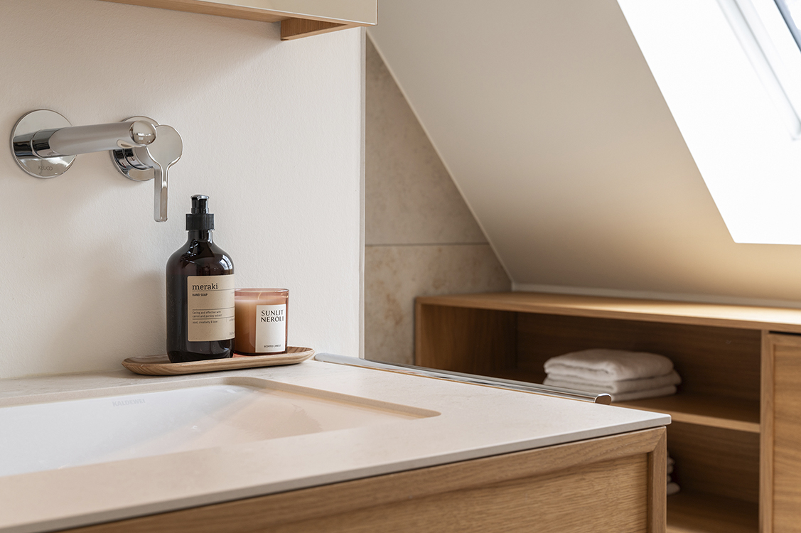 Bathroom detail with custom wooden vanity, minimal fixtures and soft light