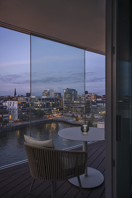 Balkon mit Blick auf Wasser und Stadt bei blauer Stunde