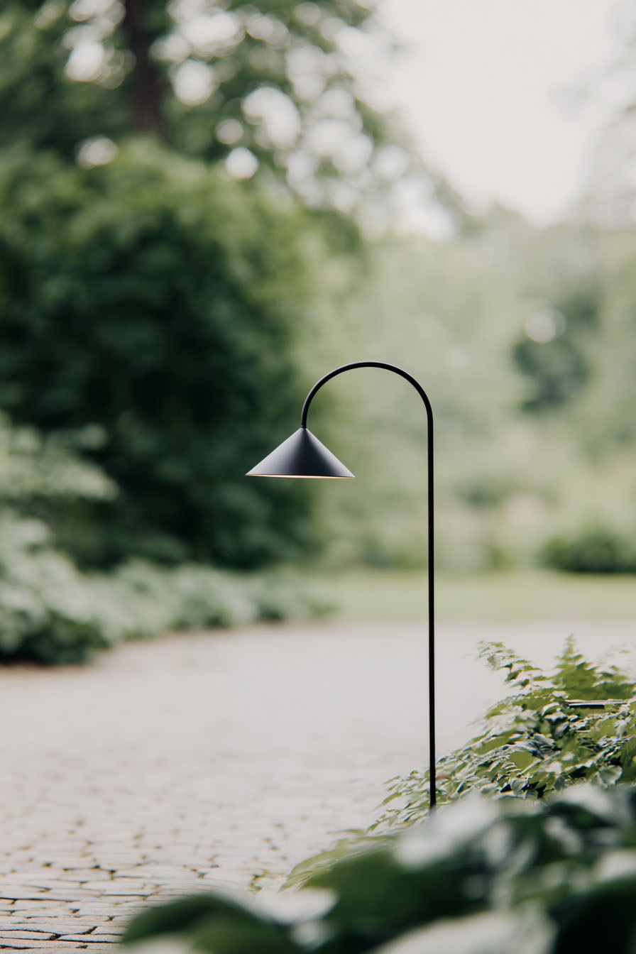 AI gestützte Gartenszene mit minimalistischer Außenleuchte im natürlichen Tageslicht umgeben von Pflanzen