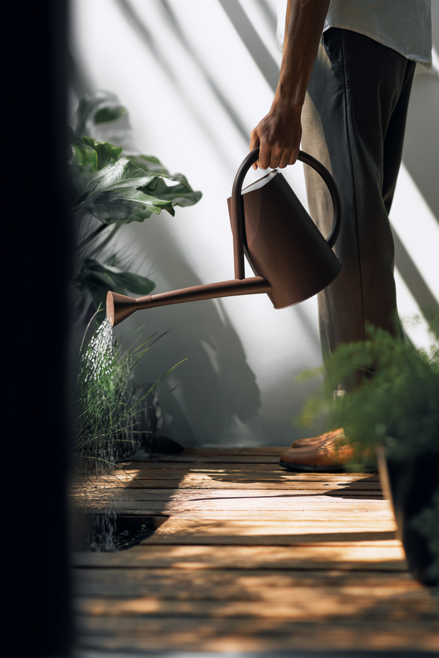 AI gestützte Outdoor Szene mit Hand und Gießkanne beim Bewässern von Pflanzen im natürlichen Tageslicht