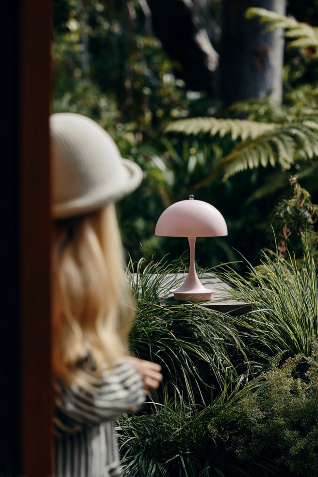 AI gestützte Gartenszene mit Kind und moderner Leuchte im natürlichen Tageslicht umgeben von Pflanzen